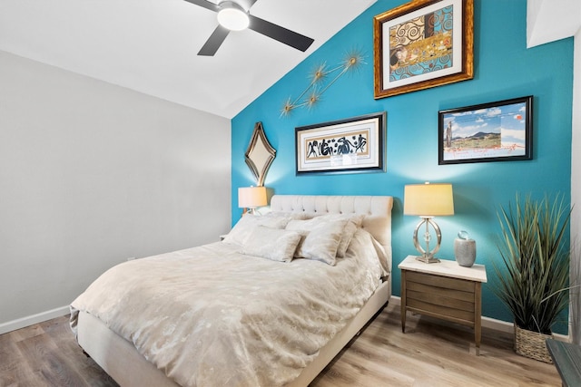 bedroom with a ceiling fan, lofted ceiling, wood finished floors, and baseboards