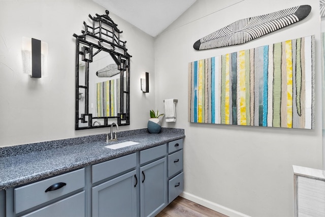 bathroom featuring baseboards, vanity, lofted ceiling, and wood finished floors