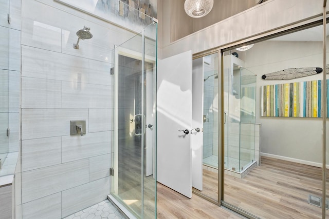 full bath featuring visible vents, a stall shower, baseboards, and wood finished floors