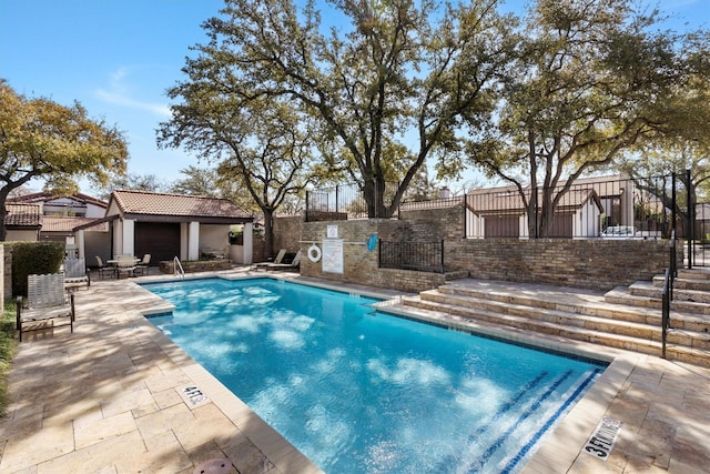 pool with a patio, a storage structure, fence, and an outdoor structure