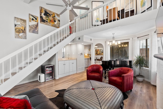 living area featuring light wood-type flooring, stairway, visible vents, and a towering ceiling