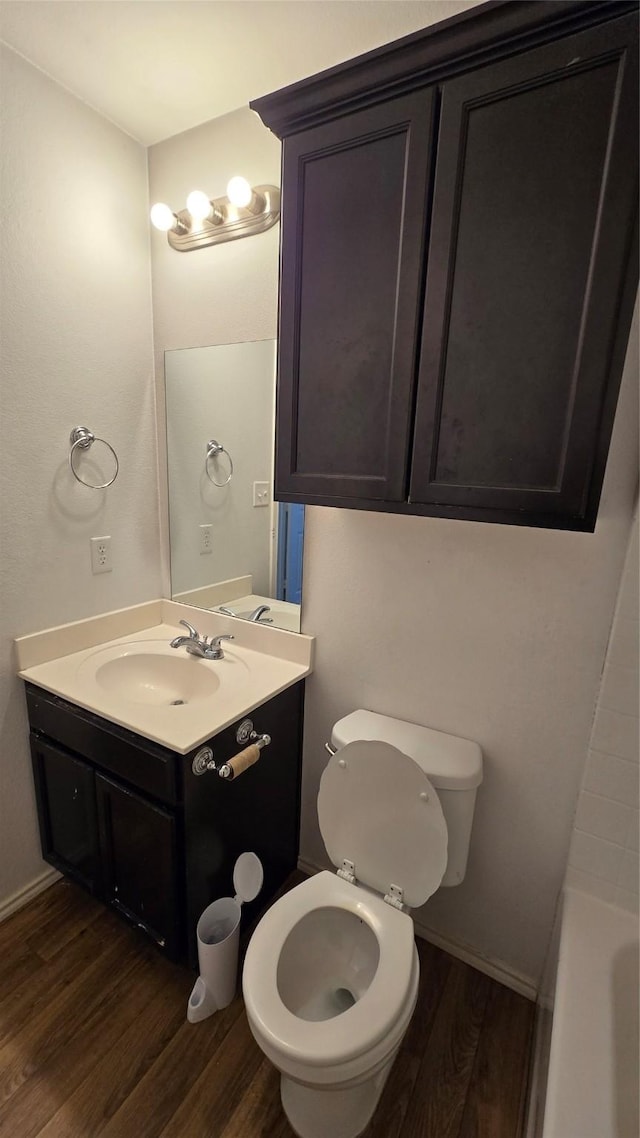 full bath featuring a bathing tub, toilet, vanity, and wood finished floors