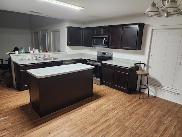 kitchen with a peninsula, light wood-style floors, visible vents, and stainless steel appliances