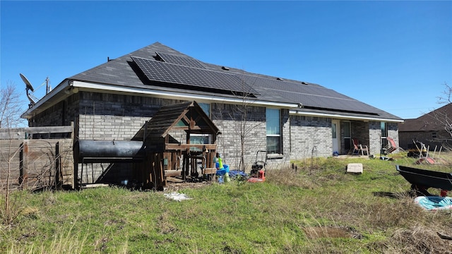 back of house featuring roof mounted solar panels