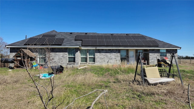 rear view of house featuring brick siding, solar panels, and a tile roof