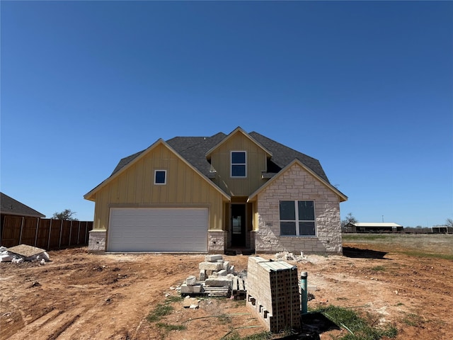 craftsman inspired home featuring driveway, stone siding, fence, board and batten siding, and an attached garage