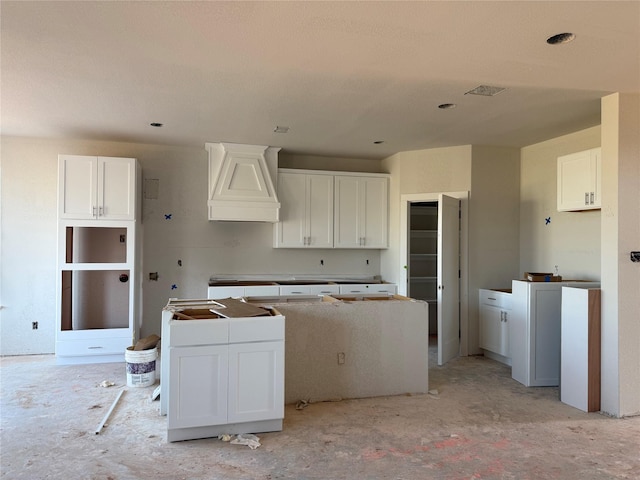 kitchen with visible vents, white cabinets, a center island, and custom range hood