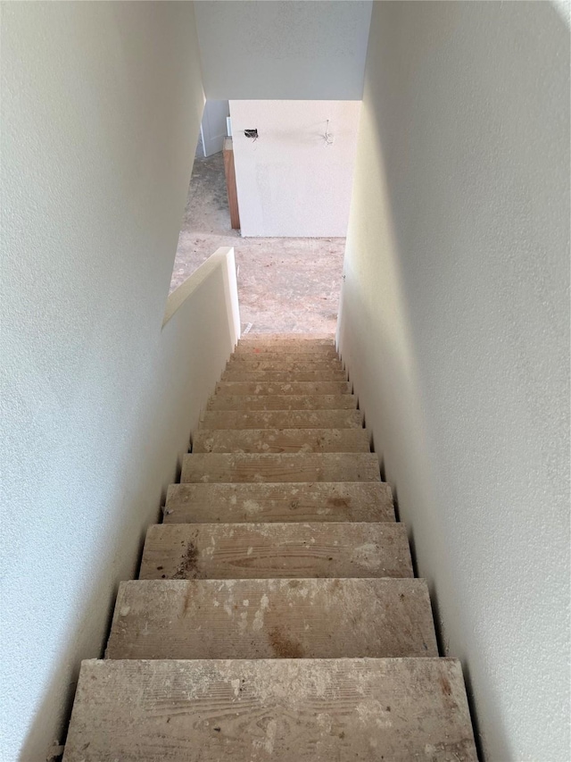 stairs featuring carpet flooring and a textured wall