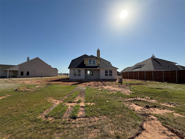 back of property featuring a lawn, fence, and a chimney