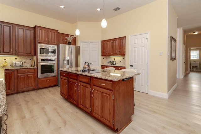 kitchen featuring visible vents, tasteful backsplash, a center island, stainless steel appliances, and light wood-style floors