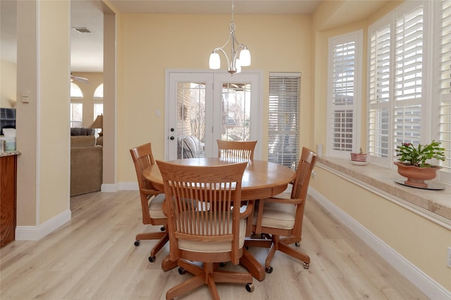 dining room with visible vents, ceiling fan with notable chandelier, light wood-type flooring, and baseboards