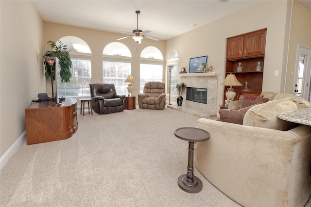 living area featuring a premium fireplace, a healthy amount of sunlight, carpet, and ceiling fan