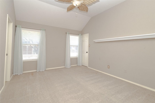 empty room featuring carpet floors, a healthy amount of sunlight, a ceiling fan, and vaulted ceiling