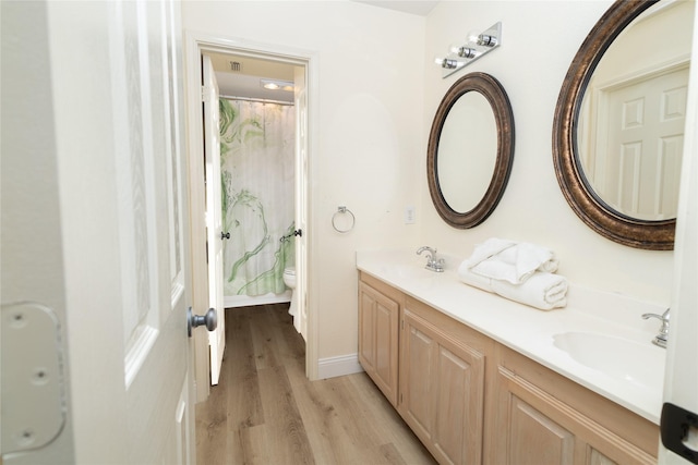 full bath with double vanity, wood finished floors, toilet, and a sink