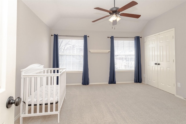 carpeted bedroom with vaulted ceiling, multiple windows, baseboards, and a closet