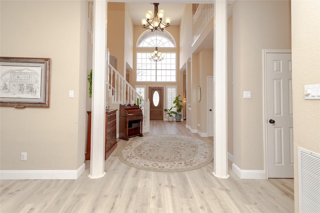 entrance foyer featuring a notable chandelier, wood finished floors, visible vents, and a towering ceiling