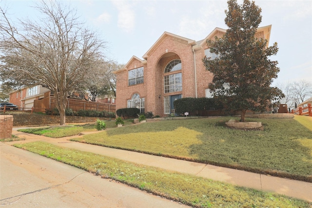 view of front of home featuring brick siding, a front yard, and fence