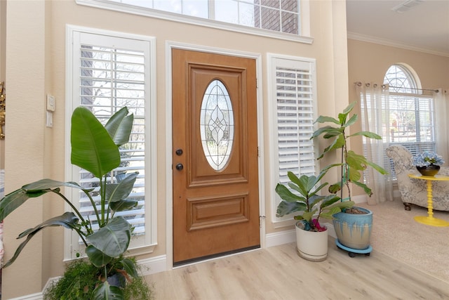 foyer with visible vents, baseboards, wood finished floors, and crown molding