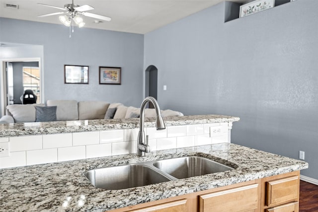 kitchen with a ceiling fan, visible vents, arched walkways, a sink, and open floor plan