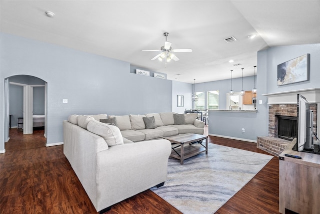 living area featuring visible vents, baseboards, dark wood finished floors, arched walkways, and a ceiling fan