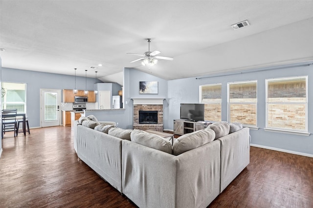 living room featuring visible vents, a brick fireplace, ceiling fan, dark wood finished floors, and vaulted ceiling