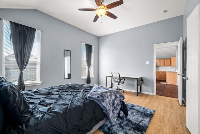 bedroom with baseboards, ceiling fan, a sink, vaulted ceiling, and light wood-type flooring