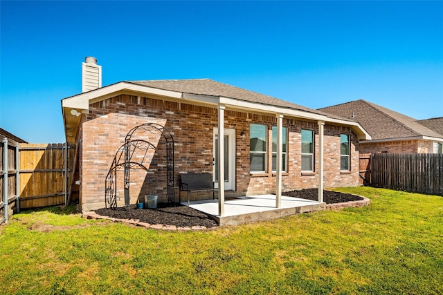 rear view of house with brick siding, a fenced backyard, and a yard