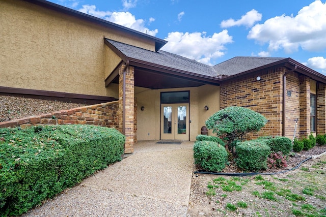 entrance to property with french doors, brick siding, and stucco siding