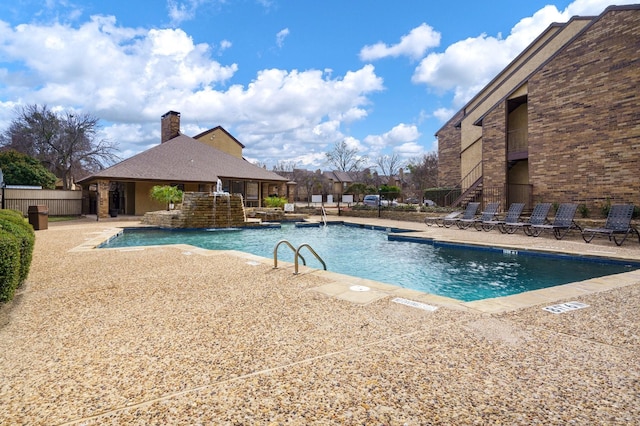 community pool with a patio area, a storage structure, an outdoor structure, and fence