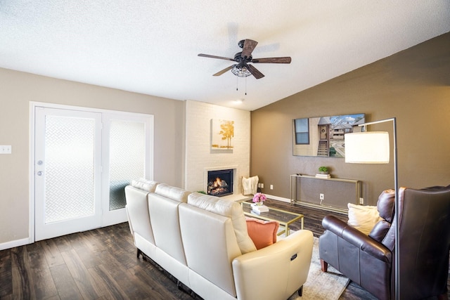 living area featuring a brick fireplace, baseboards, lofted ceiling, dark wood-style floors, and a ceiling fan