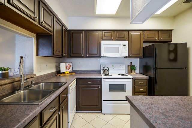 kitchen featuring visible vents, a sink, white appliances, dark brown cabinetry, and light tile patterned floors