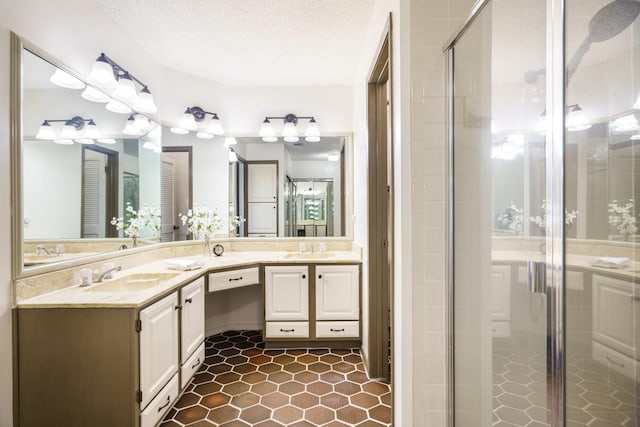 full bath featuring double vanity, a shower stall, a textured ceiling, and a sink