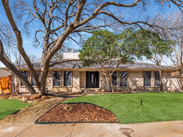 single story home featuring a front yard, brick siding, and a shingled roof