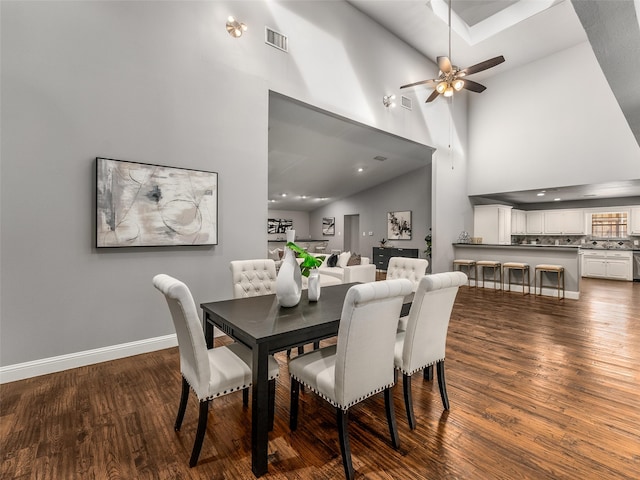 dining space with visible vents, baseboards, ceiling fan, wood finished floors, and high vaulted ceiling