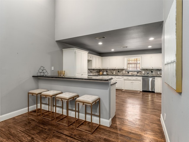 kitchen featuring dark wood finished floors, white cabinets, dishwasher, dark countertops, and backsplash