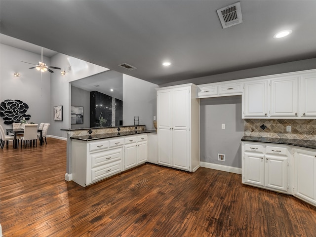 kitchen with white cabinetry, a peninsula, visible vents, and dark wood-style flooring