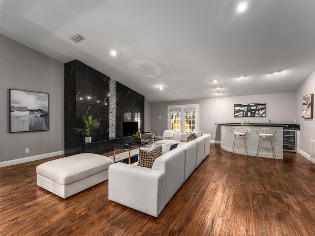 living room featuring wood finished floors, visible vents, baseboards, a bar, and vaulted ceiling