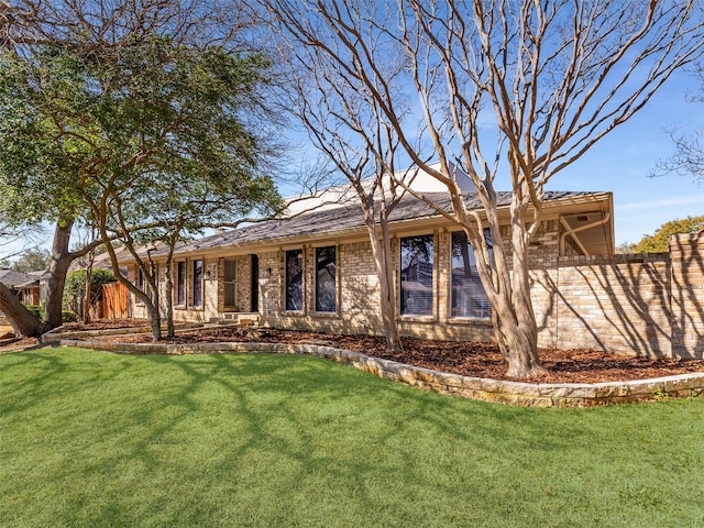 ranch-style home with a front lawn, fence, and brick siding