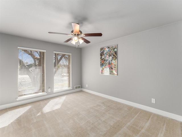 carpeted empty room featuring visible vents, baseboards, and ceiling fan