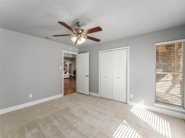 unfurnished bedroom featuring baseboards, visible vents, ceiling fan, a closet, and carpet flooring