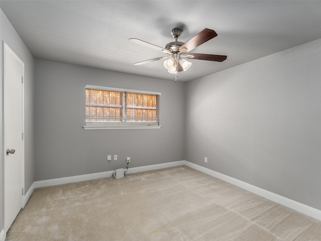 carpeted spare room with baseboards and a ceiling fan