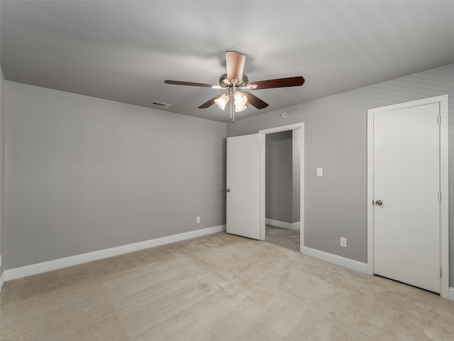 unfurnished bedroom featuring a ceiling fan, light colored carpet, visible vents, and baseboards