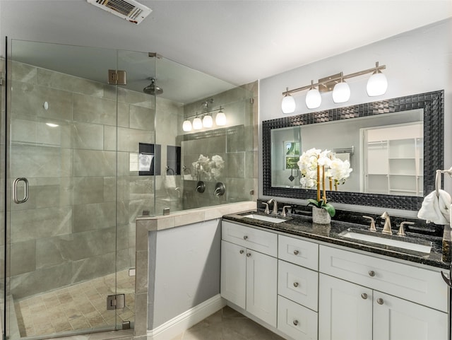 full bath with double vanity, visible vents, a stall shower, and a sink