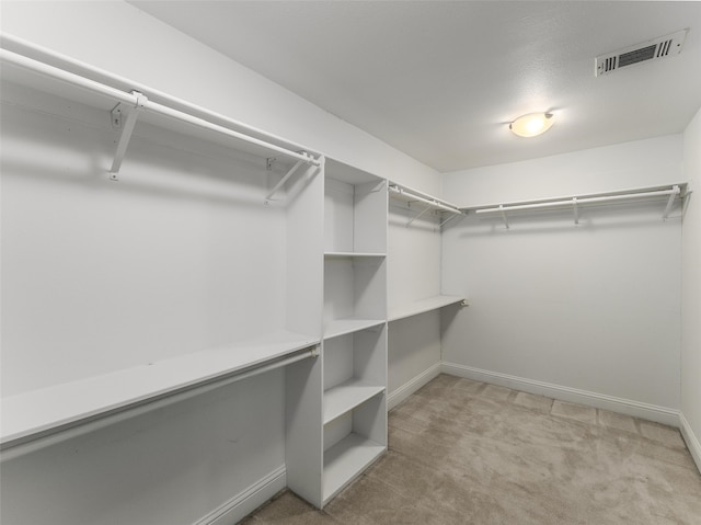 walk in closet with visible vents and light carpet