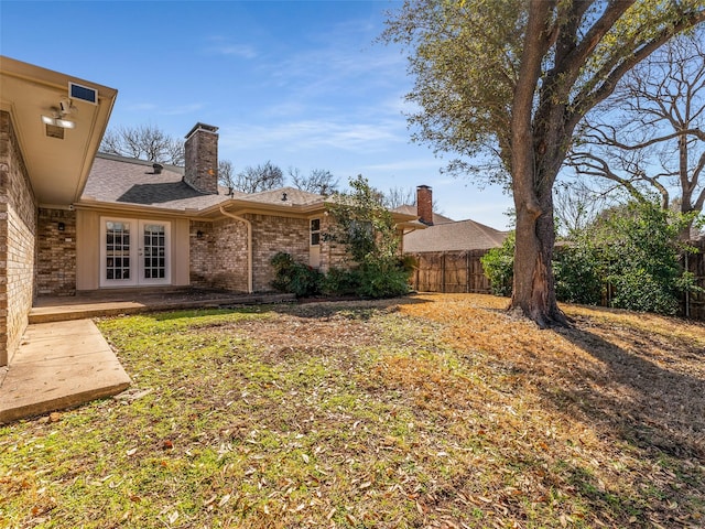 view of yard with french doors and fence