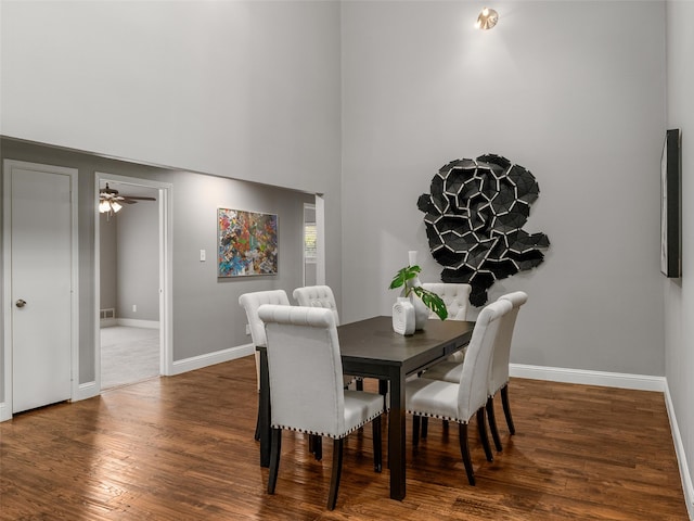 dining room with wood finished floors, baseboards, a towering ceiling, and ceiling fan