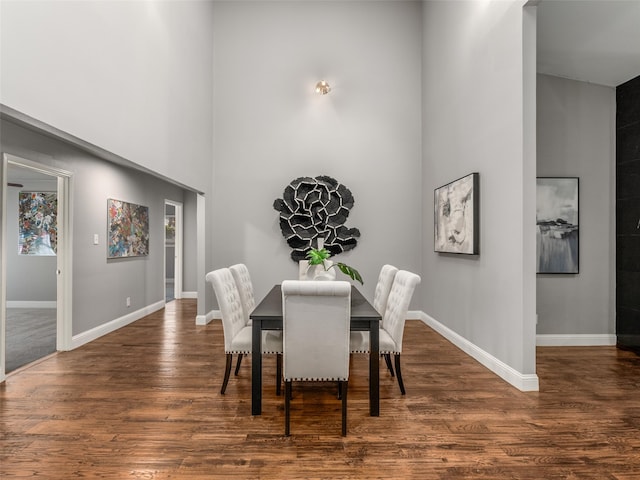 dining space featuring a high ceiling, wood finished floors, and baseboards