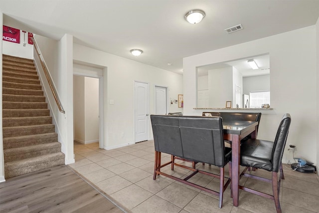 dining room featuring light tile patterned floors, visible vents, stairway, and baseboards