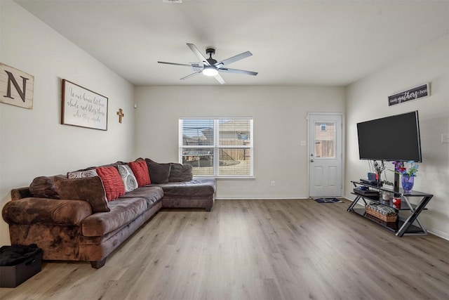 living area featuring light wood finished floors, baseboards, and a ceiling fan