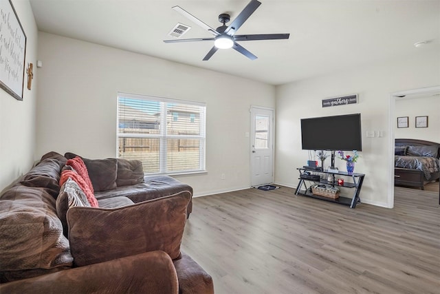 living room with wood finished floors, a ceiling fan, visible vents, and baseboards